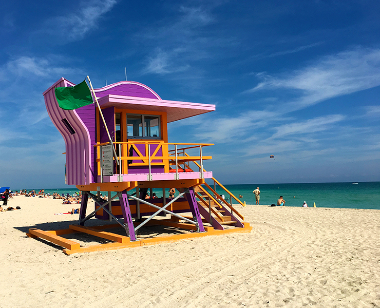 Lifeguard tower in pink color inspired by art deco with green flag symbol of perfect swimming conditions, Miami South Beach famous vacation holidays destination landmark